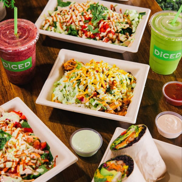 Diced's healthy bowls, wraps, and smoothies are arranged on a wooden table.
