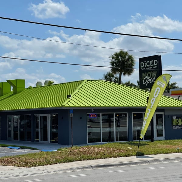 The Diced restaurant exterior with a bright green roof, black sign, and "NOW Open" flag.