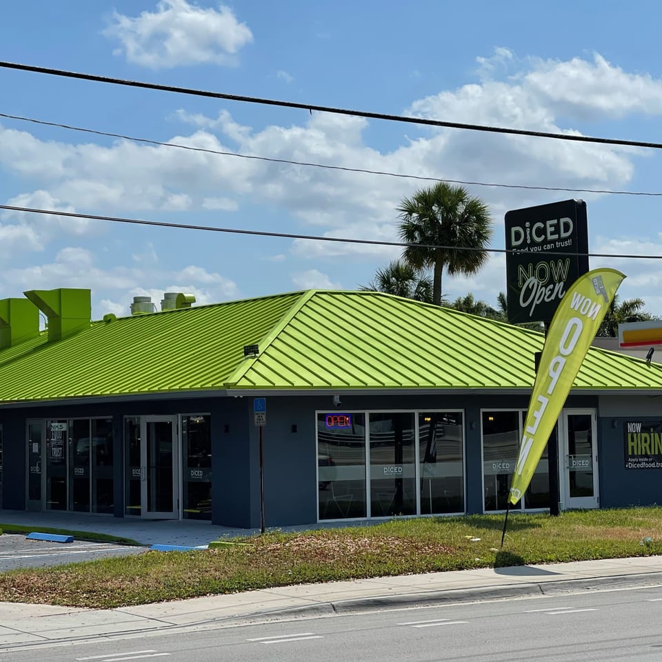 The Diced restaurant exterior with a bright green roof, black sign, and "NOW Open" flag.
