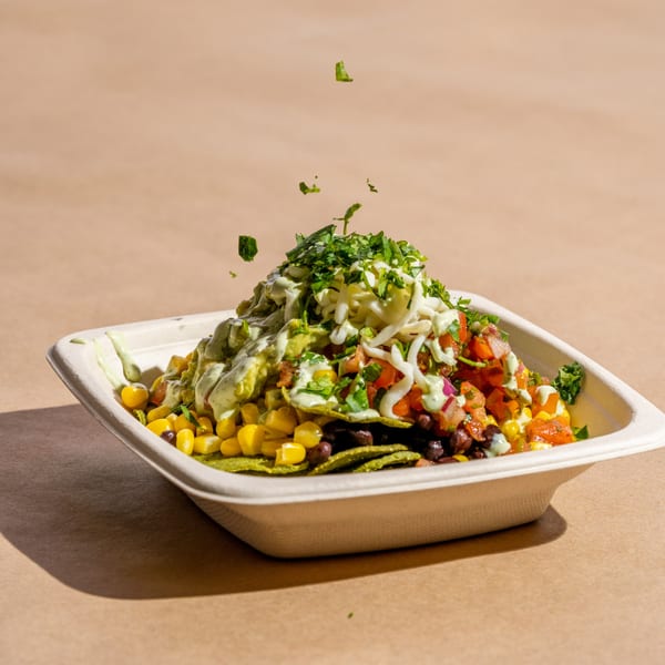 A Diced healthy bowl with corn, black beans, pico de gallo, guacamole, cheese, and cilantro.