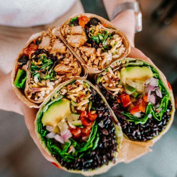 Four Diced burritos, two with chicken and two vegetarian, held in hands, showcasing fresh ingredients.