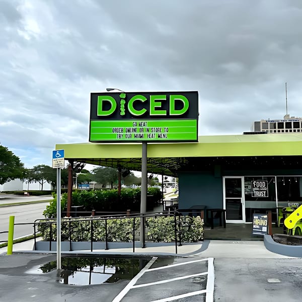 Exterior of Diced restaurant with a large green sign, green awning, and a parking lot.