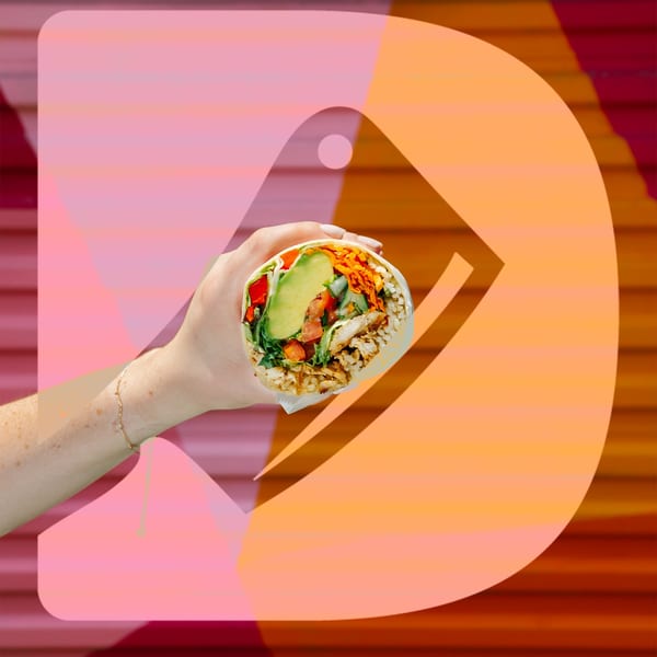 A hand holds a Diced healthy burrito, filled with chicken, avocado, rice, and vegetables.