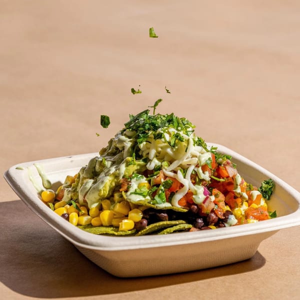 Diced's healthy nachos with corn, black beans, salsa, guacamole, cheese, and cilantro in a bowl.